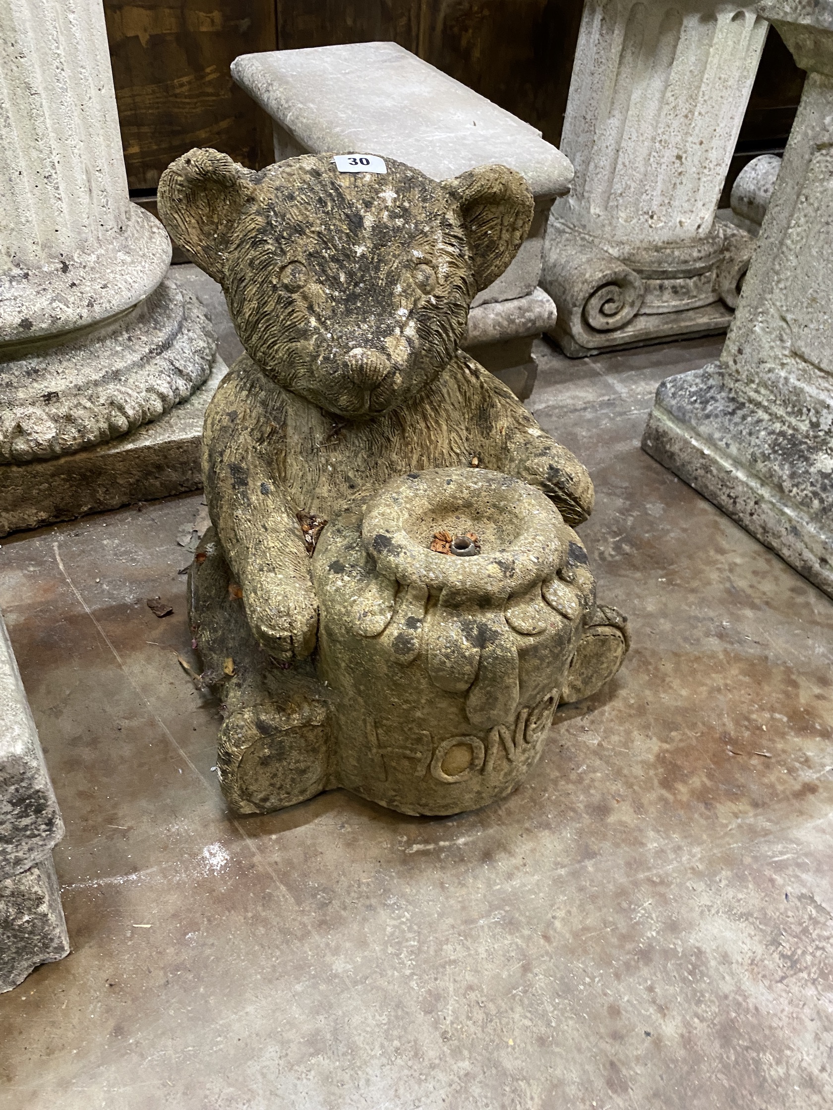 A reconstituted stone garden fountain modelled as a bear with a honeypot, height 37cm